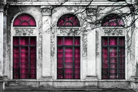 Facade of old abandoned building with three large arched windows of pink glas Stock Photos