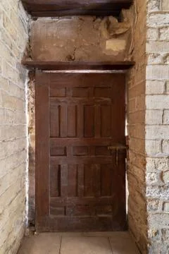 Facade of old abandoned stone bricks wall with grunge weathered wooden door Stock Photos