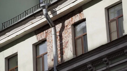 Facade of old beige red brick building with several windows and rain gutter pipe Stock Footage 107111870