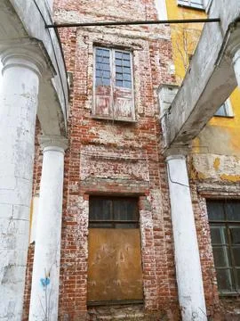 The facade of an old brick building with columns, scuffed walls and a board.. Stock Photos