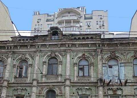 The facade of an old building against the backdrop of a high-rise modern house 库存照片