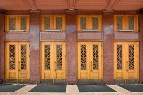 Facade of old building is lined with marble entrance wooden doors. Stock Photos