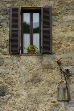 Facade of an old house with a window featuring open shutters Stock Photos