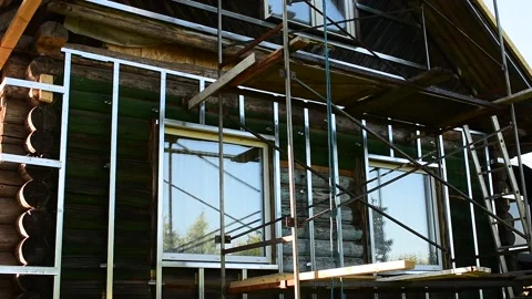 Facade of an old log house with new windows, prepared for cladding, renovation c Stock Footage 148010981