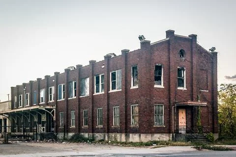 Facade of an old spacious damaged brick building with broken windows against a Fotos de archivo