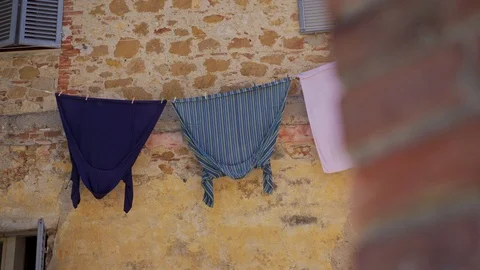 Facade of old stone house with washed colored clothes drying on rope outside 库存影片 124170993
