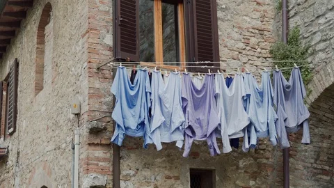 Facade of old stone house with washed blue shirts drying on rope on sunny day Stock-Footage 125492076