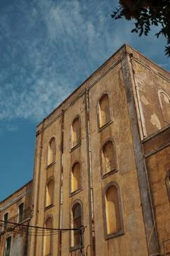 Facade of an old weathered building with arched window frames against a blu.. Stock Photos