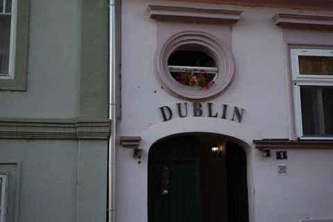 Facade of a pink building features a circular window above an arched entrance Stock Photos