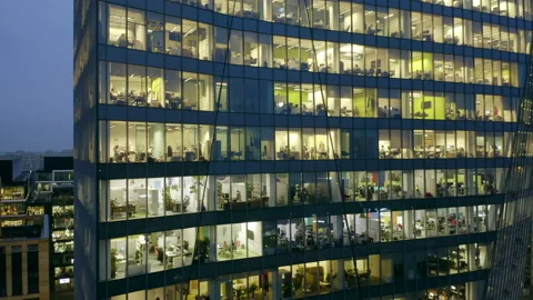Facade of a skyscraper at night with office windows and people working late. Vídeo Stock 173085116