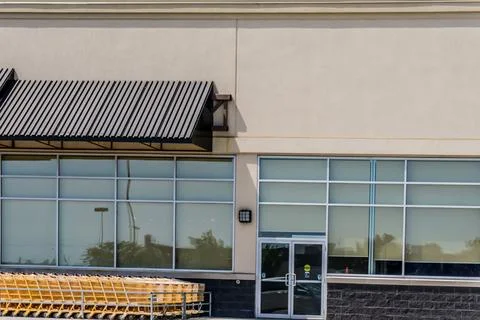 Facade of a store with reflective windows and yellow carts parked on the side Stock Photos