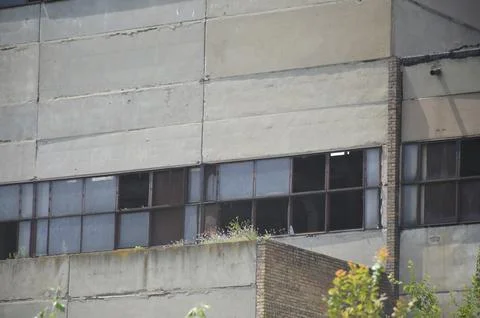 Facade wall of an abandoned and destroyed factory with empty windows Stock Photos