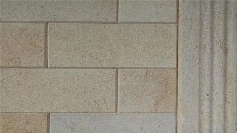 Facade wall made of stone yellow beige tiles. Decoration of buildings Illustrazione stock