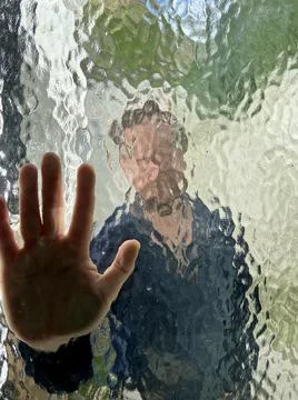 Face and hand in wavy pattern glass window with blurred and distorted face  Stock Photos