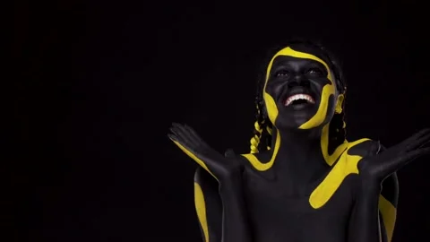 Face art. Woman with black and yellow body paint. Young african
