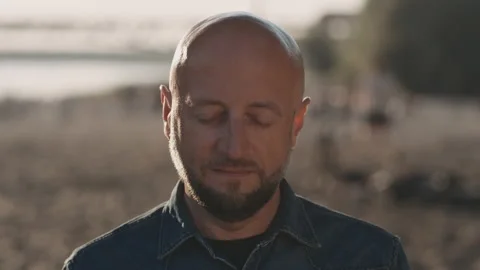 Face of bald hipster with a stylish beard is standing on the beach during a Stock Footage 140132396