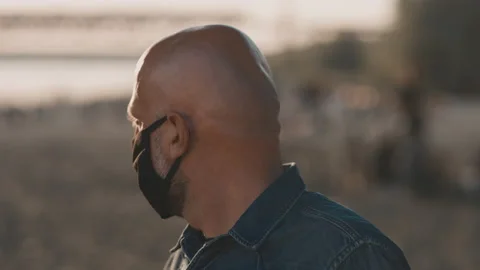 Face of a bald man at the beach during the sunset. He is wearing mask and he is Stock Footage 137253832