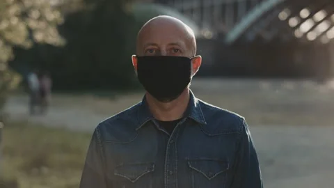Face of a bald man in the park. He is wearing black mask and he is closing his Stock Footage 135405294