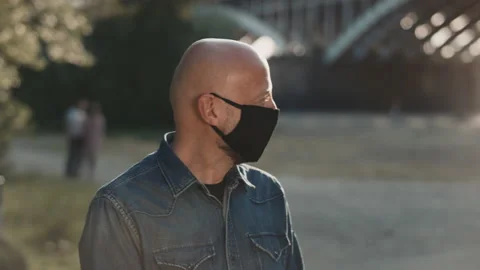 Face of a bald man in the park. He is wearing mask and he is turning his head Stock Footage 146522764