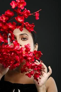 Face of a beutiful female model behind a bunch of red flowers shot in a stu.. Stock Photos