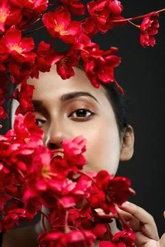 Face of a beutiful female model behind a bunch of red flowers shot in a stu.. Stock Photos