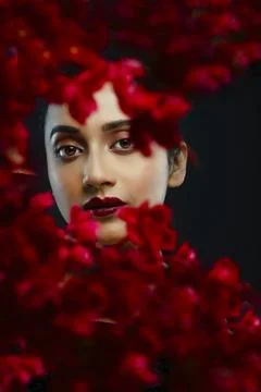 Face of a beutiful female model behind a bunch of red flowers shot in a stu.. Stock Photos