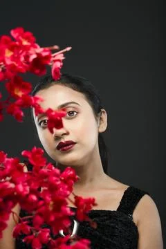 Face of a beutiful female model behind a bunch of red flowers shot in a stu.. Stock Photos