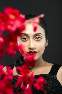 Face of a beutiful female model behind a bunch of red flowers shot in a stu.. Stock Photos