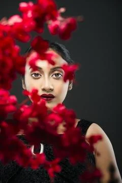 Face of a beutiful female model behind a bunch of red flowers shot in a stu.. Stock Photos