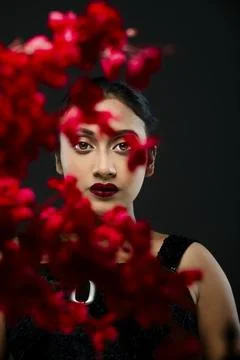 Face of a beutiful female model behind a bunch of red flowers shot in a stu.. Stock Photos