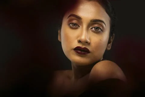 Face of a beutiful female model behind a bunch of red flowers shot in a stu.. Stock Photos