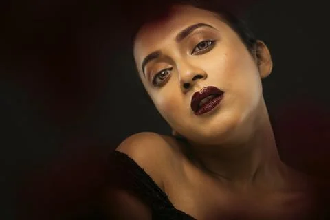 Face of a beutiful female model behind a bunch of red flowers shot in a stu.. Stock Photos