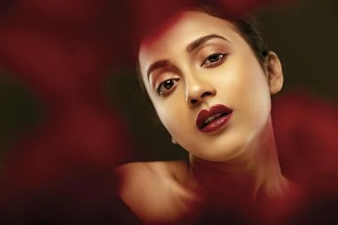 Face of a beutiful female model behind a bunch of red flowers shot in a stu.. Stock Photos