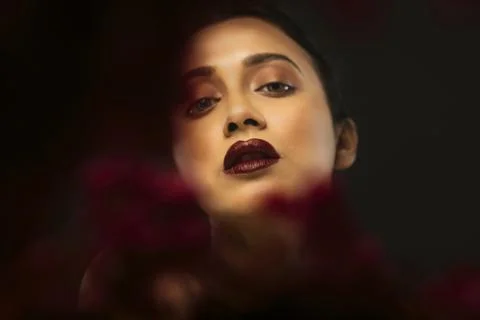 Face of a beutiful female model behind a bunch of red flowers shot in a stu.. Stock Photos