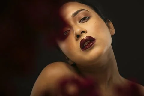 Face of a beutiful female model behind a bunch of red flowers shot in a stu.. Stock Photos