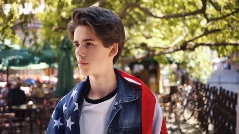 Face boy with american flag look at camera serious shot in slow motion in park Stock Footage 92052829