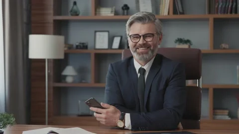 Face businessman with glasses using his smartphone sitting at table looking at Vídeos de archivo 220191002