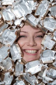 The face of a Caucasian woman surrounded by candy wrappers. Stock Photos