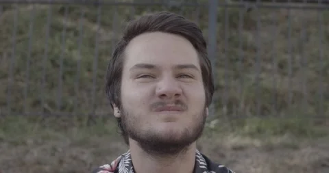 Face close up of young man winking his nose and laughing Stock Footage 136897904