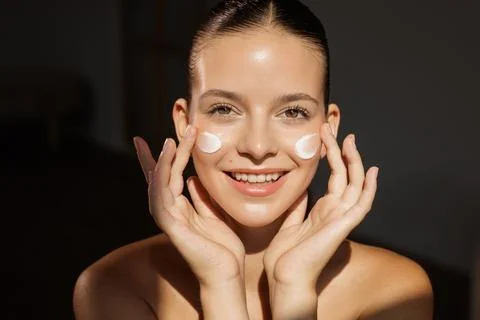 Face cream application skincare routine with smiling young woman 스톡 사진