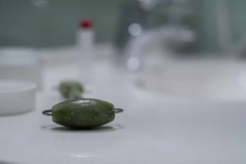 Face cream, face roller and lipstick near the sink on the counter in the bath Stock Photos