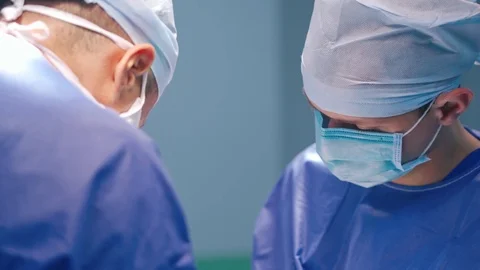 Face of a doctor in mask looking down. Side view of two surgeons Stock Footage 125894901