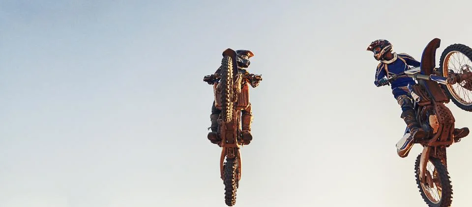 Face-to-face while flying through the air. Two motocross riders clearing a jump Stock Photos