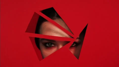 Face of girl appears in triangular holes of red paper background. Stock Footage 86533622