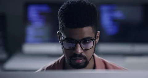 Face, glasses and programming with a black man coder working in a dark office Stock Footage 241889618