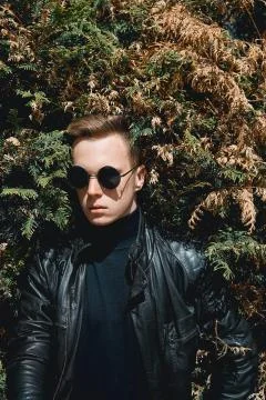 The face of the guy with glasses on the background of bushes Stock Photos