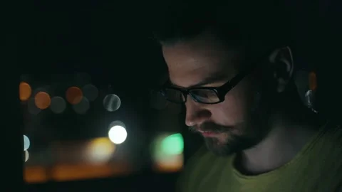 The face of a guy in glasses illuminated by the light from the phone screen. Stock Footage 237240489