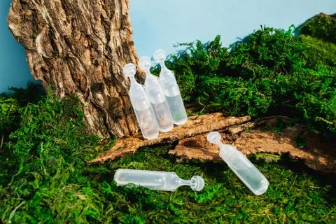 Face, hair, medical ampoule cosmetic bottles on green forest landscape. Modern Stock Photos