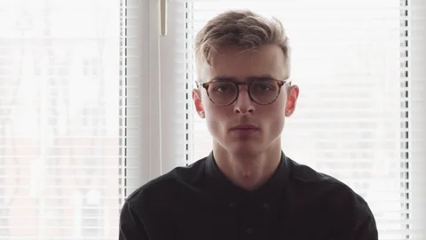 Face of a handsome young man in glasses against the window Video stock 86209273