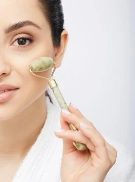 Face jade roller. Cropped half face of a Hispanic woman with jade or stone ro Stock-Fotos